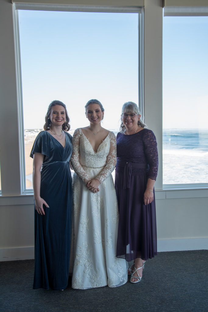 bride with her mom and sister with ocean in the background at winter oceanside wedding 