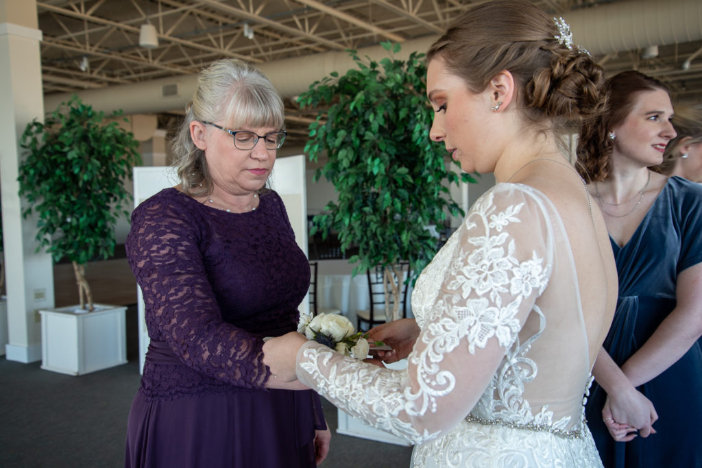 bride putting on her mom's corsage at winter oceanside wedding 