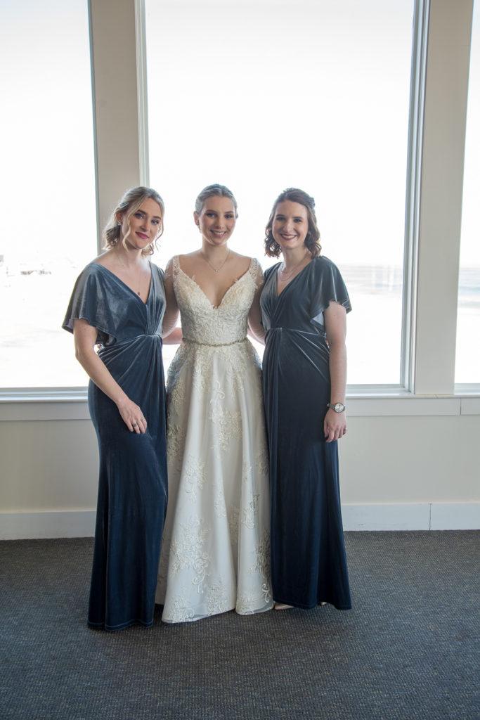 bride with her bridesmaids at winter oceanside wedding 