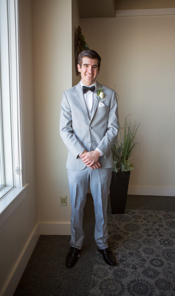 groom posing by the window smiling 