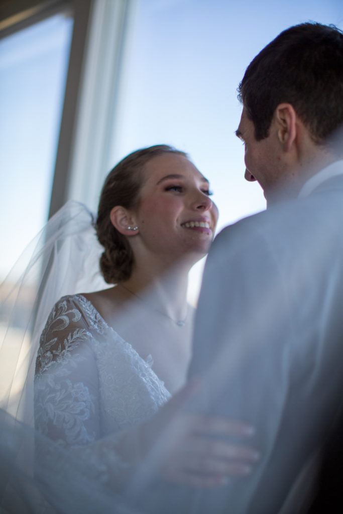 bride looking at groom, smiling. shot taken through the veil 