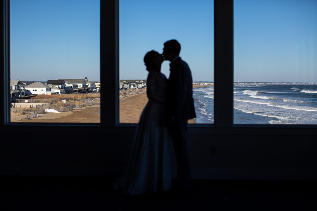 silhouette of bride and groom with ocean in the background at winter oceanside wedding  