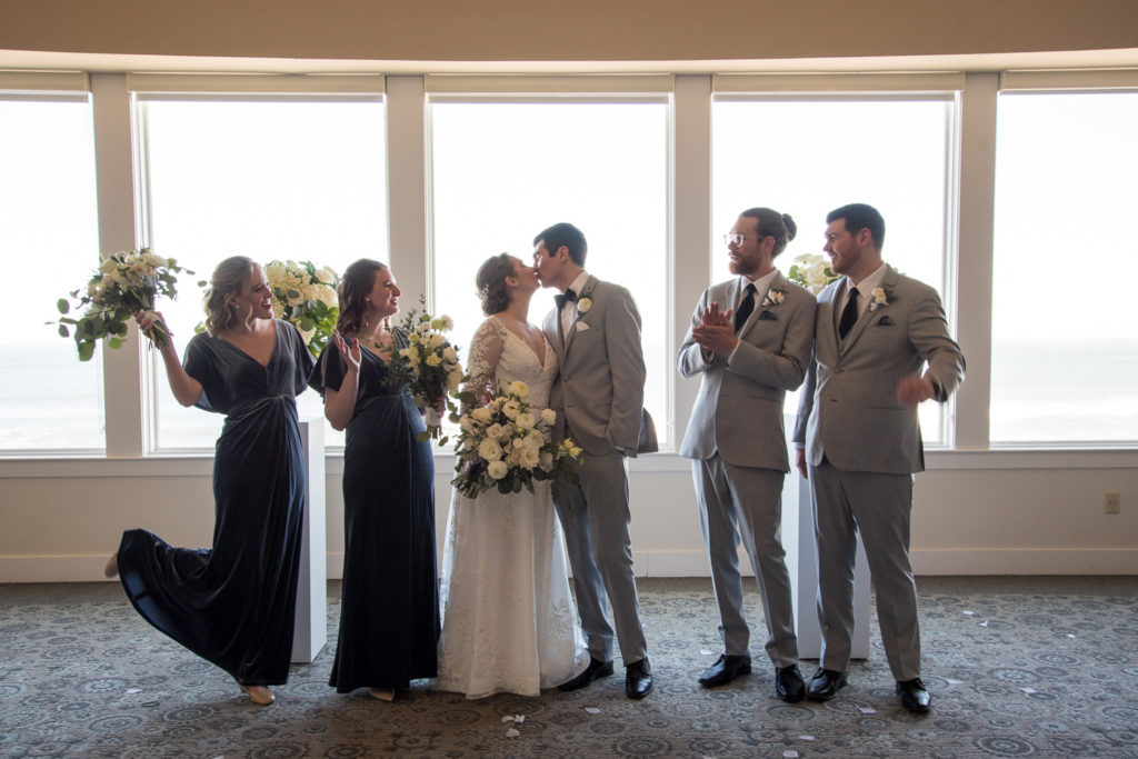 bridal party cheering as bride and groom kiss