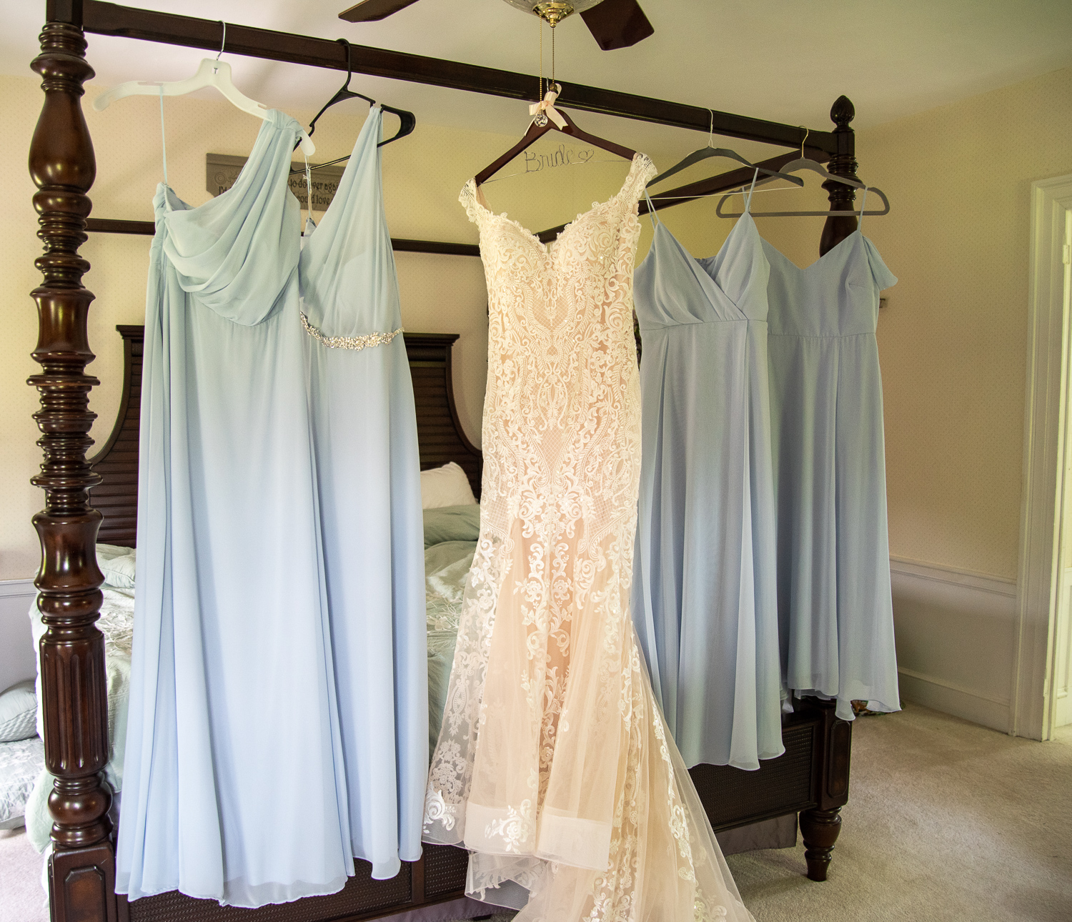 bride and bridesmaids dresses hanging on the bed 