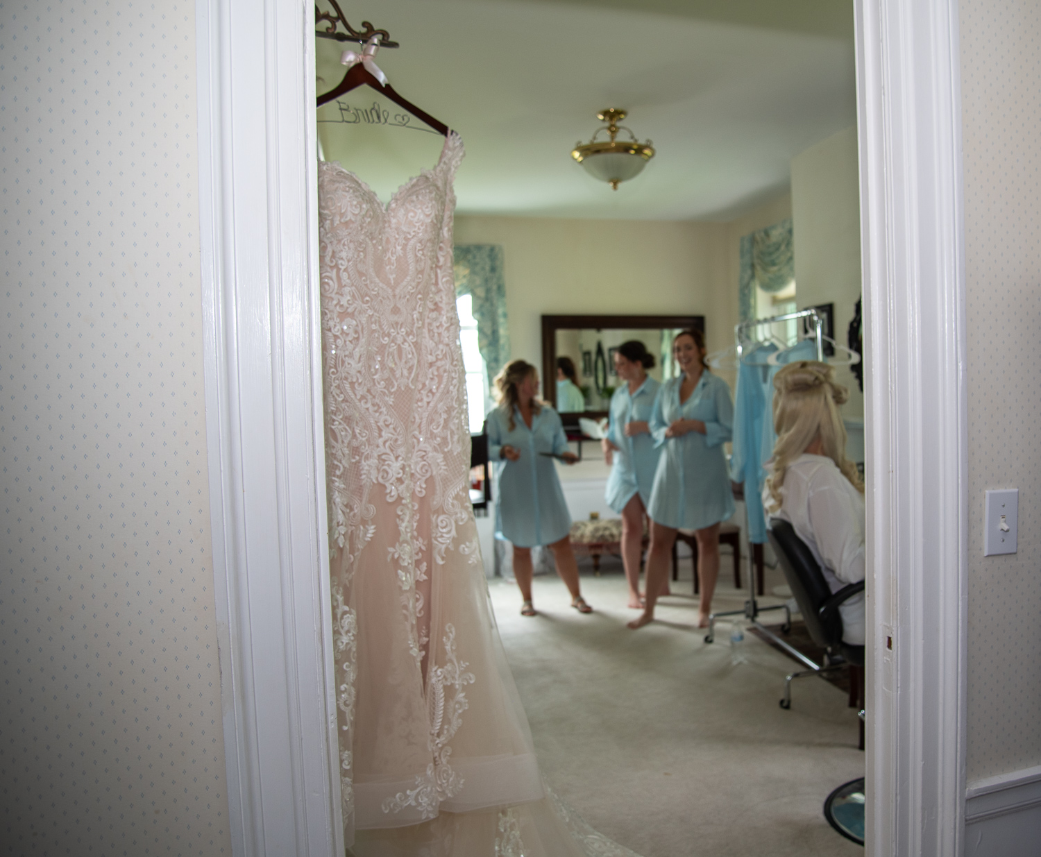 wedding dress in focus with bride and bridesmaids in the background