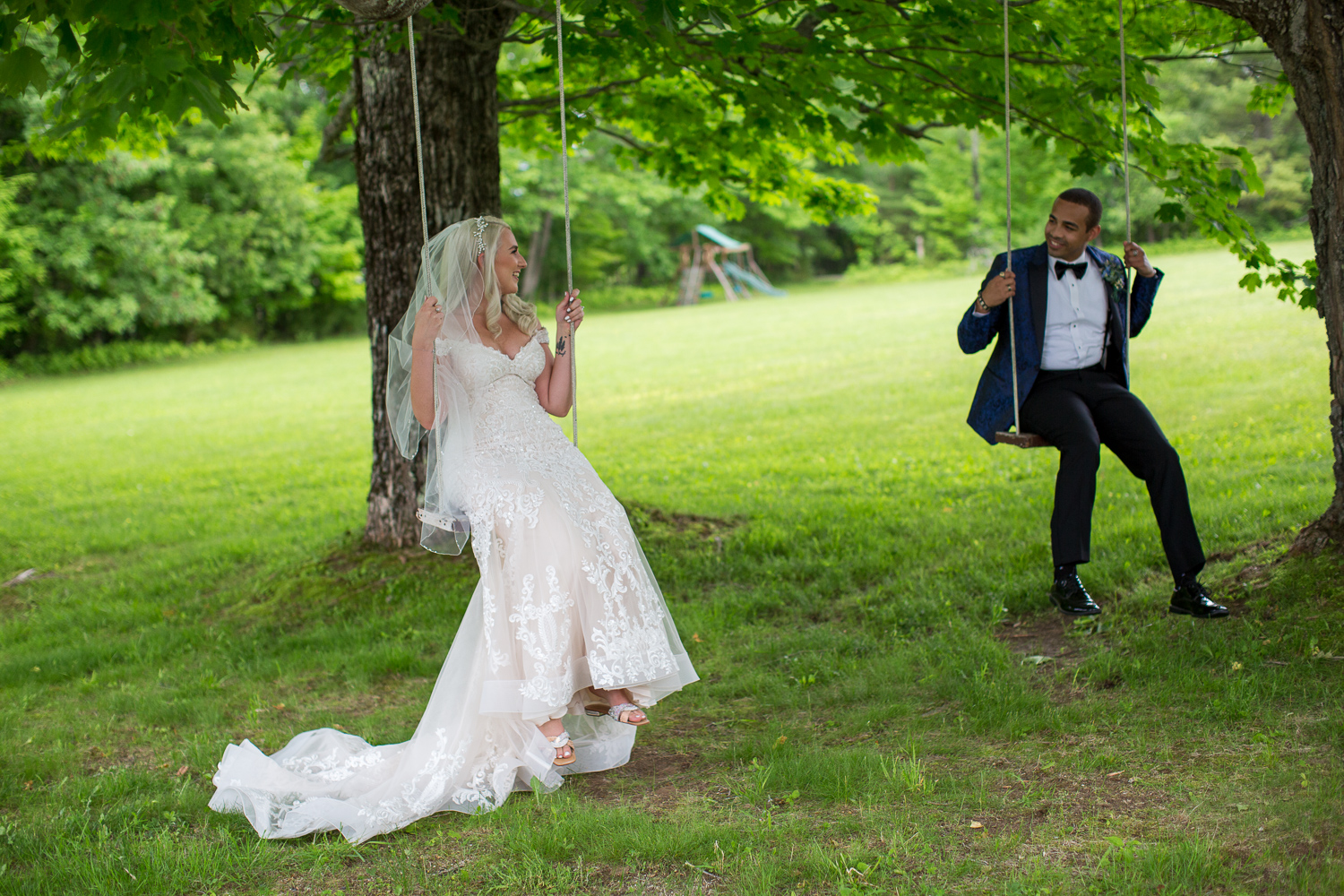 bride and groom sitting on tree swings looking at each other on the perfect day 