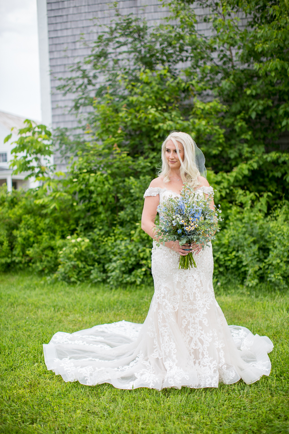 bride posing with her bouquet in front of Whitney Farm Estate barn at the perfect day