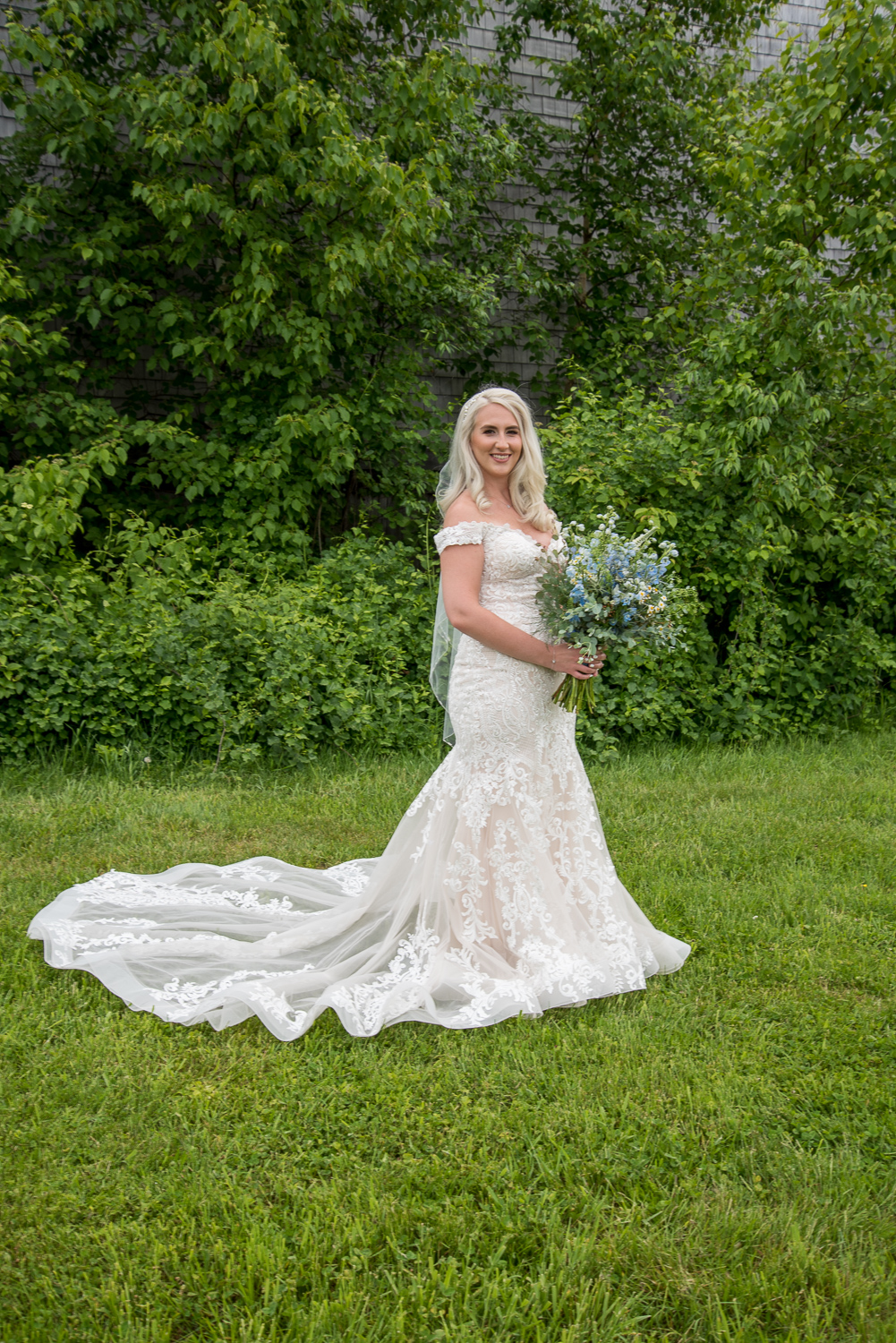 bride posing with her bouquet in front of Whitney Farm Estate barn at the perfect day