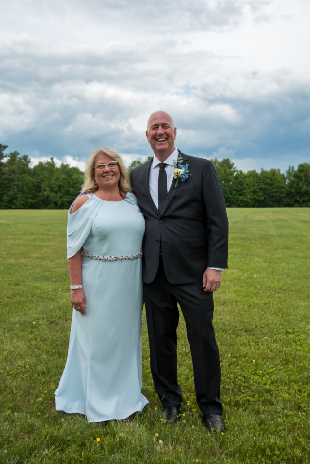 mother and father of the bride in a field with dark storm clouds in the background at the perfect day