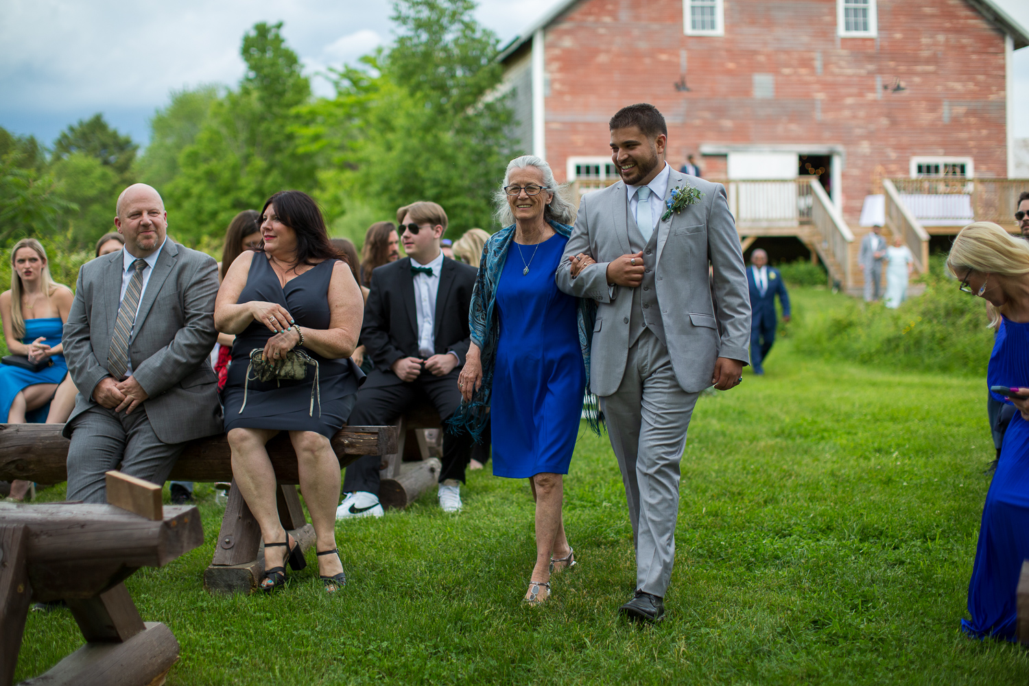grandmother of the groom walking down the aisle escorted by groomsman at the perfect day