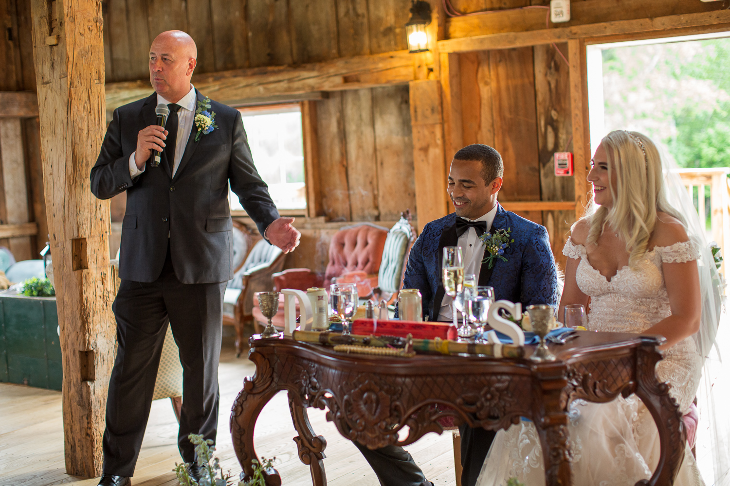 father of the bride giving a toast with bride and groom sitting at sweetheart table at the perfect day 
