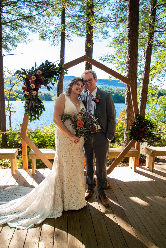 bride and groom in front of the wedding arbor and lake at a weekend wedding at camp