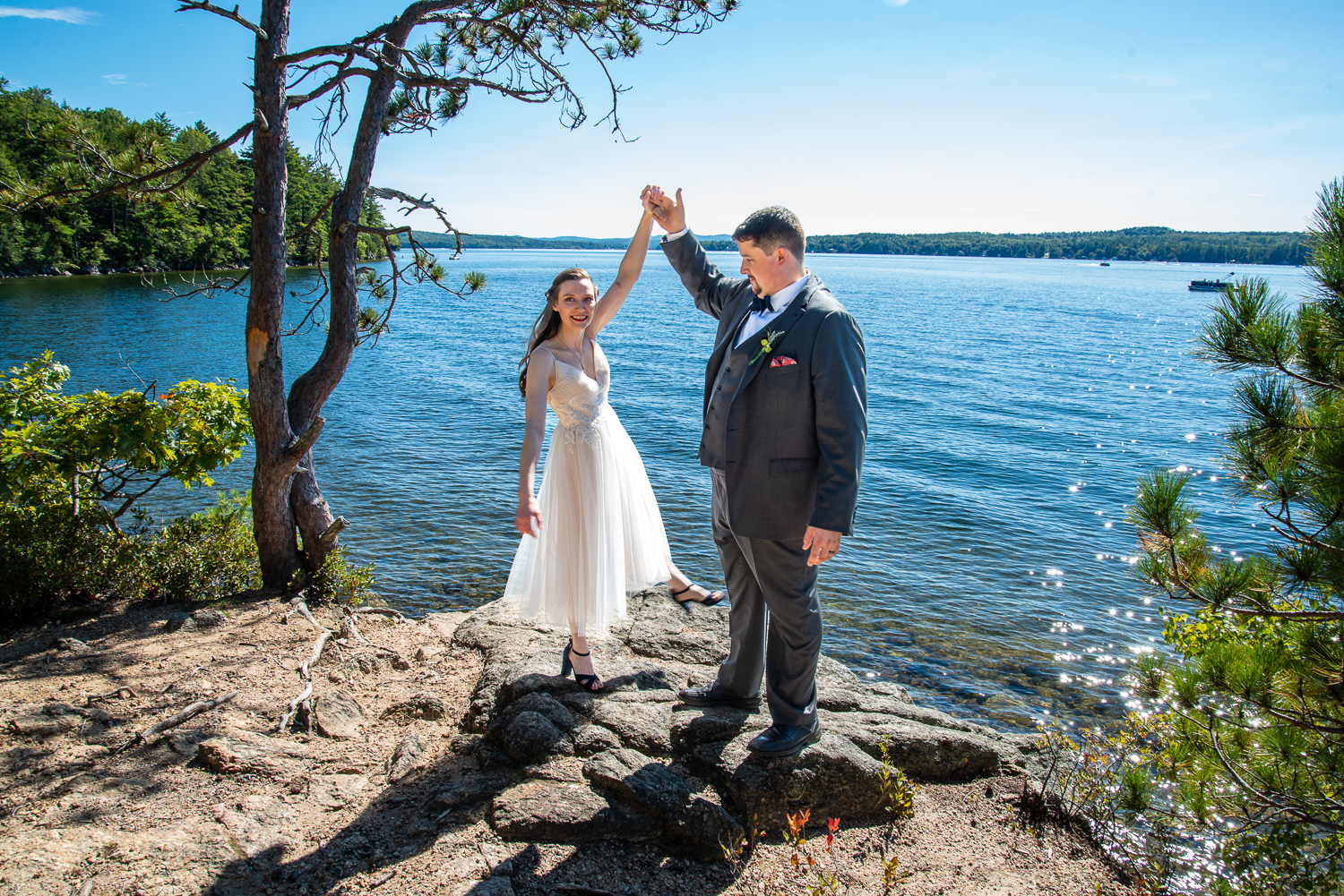 groom twirling his bride in front of the lake at their September wedding