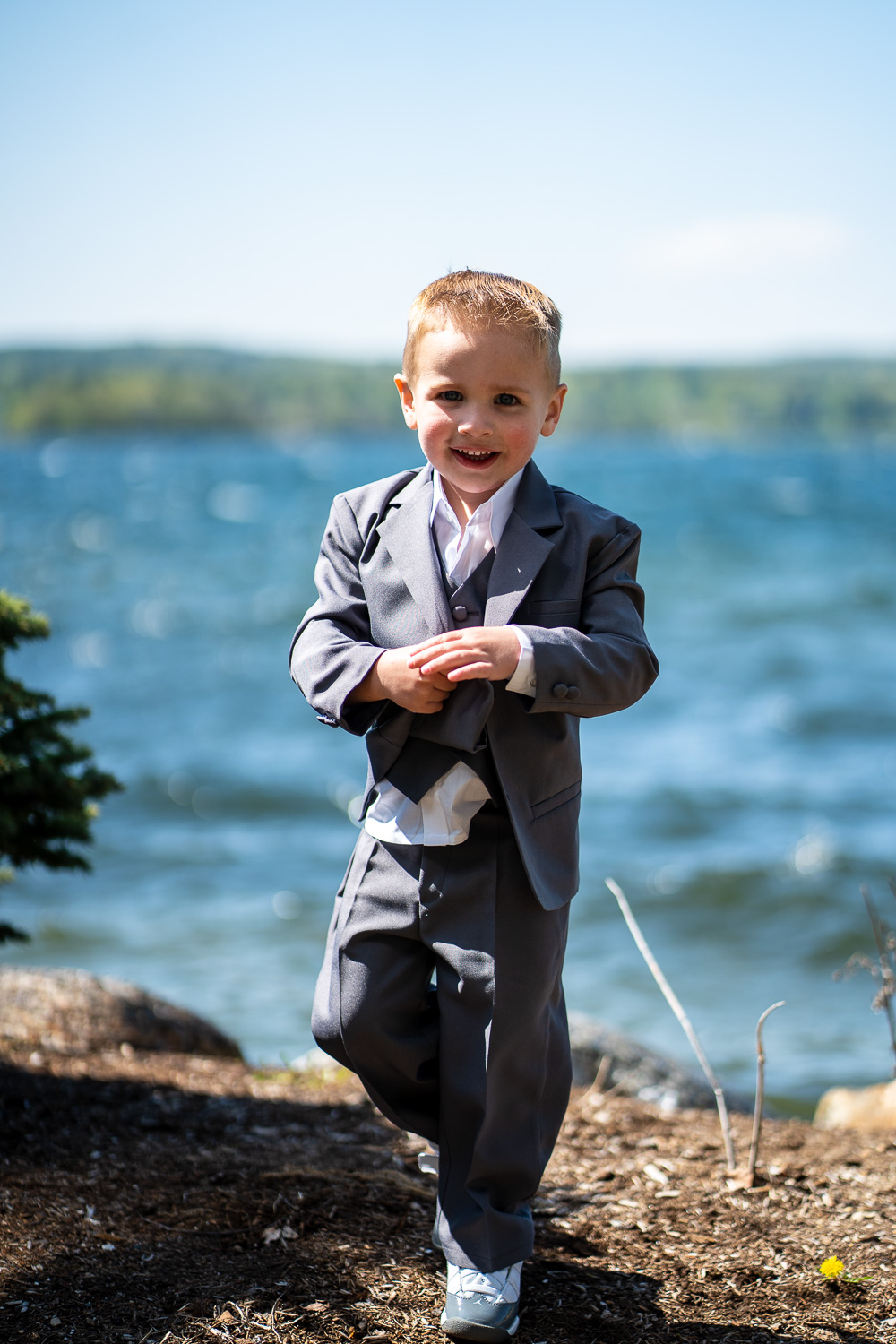ring bearer posing in front of the lake before the lakeside wedding 
