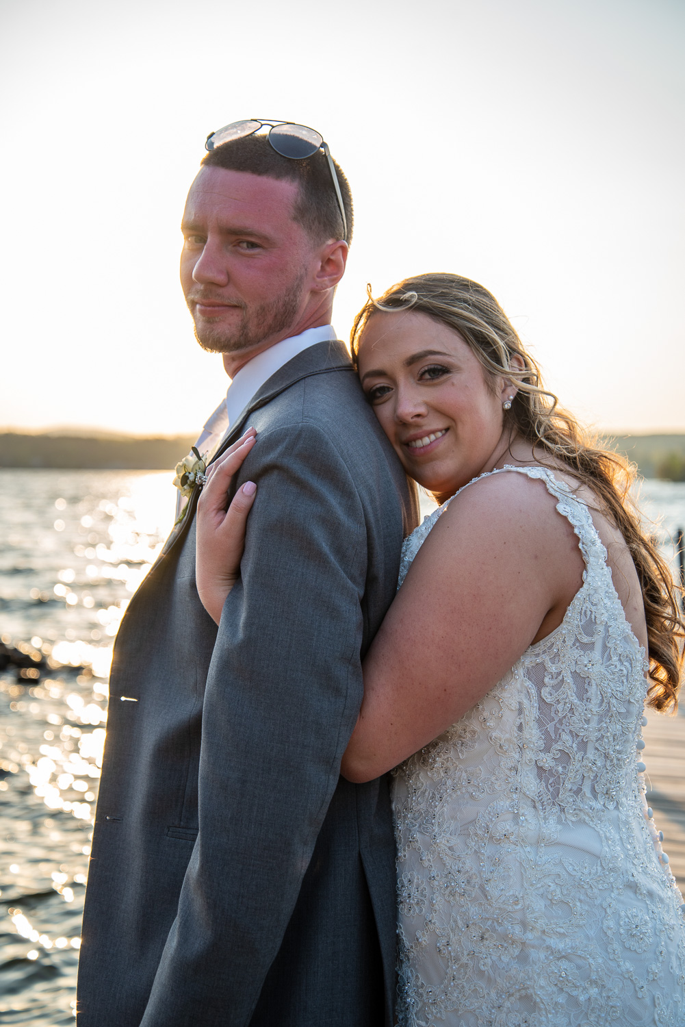 Bride with her arms wrapped around the groom on the dock of the lakeside wedding