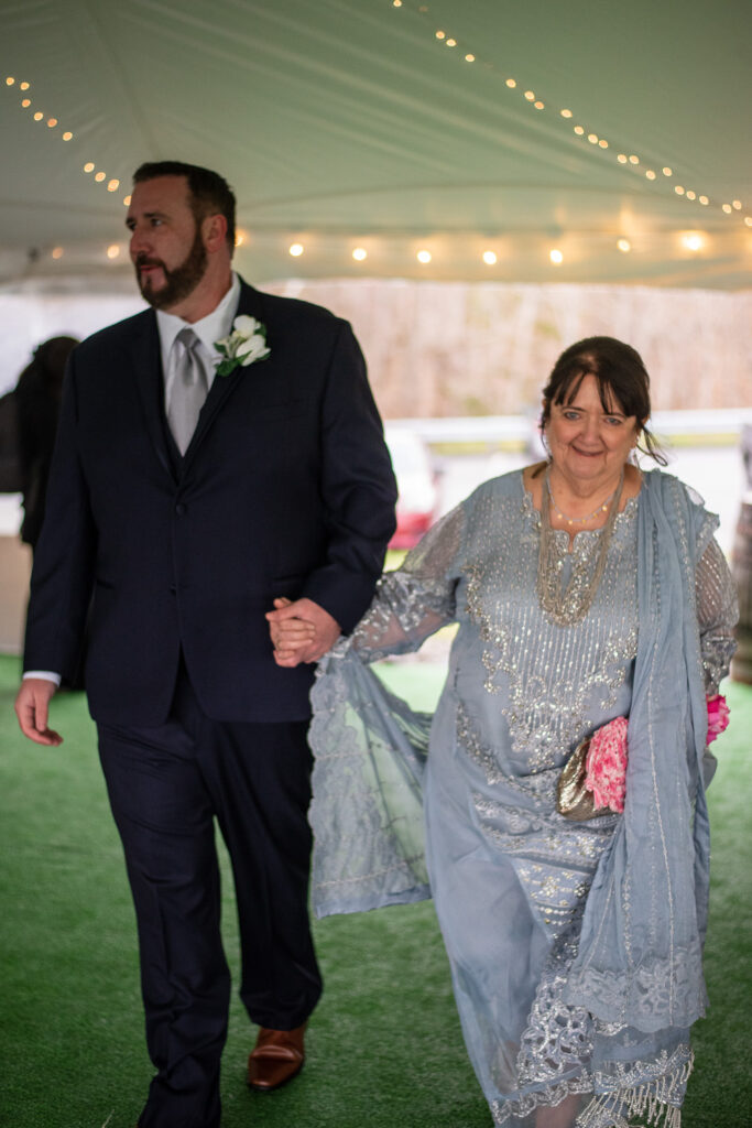 groom walking hand in hand with his mom coming down the aisle at a wedding with a view  