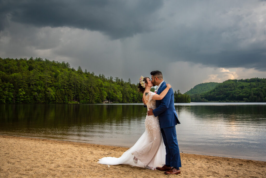 The Bride and groom kissing with intense clouds and the lake in the background on the sweetest wedding day